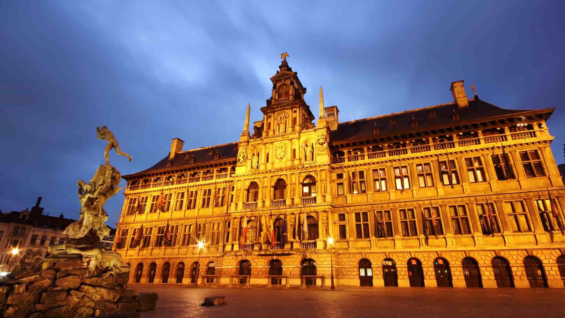 The city hall of Antwerp, Belgium, showcases a large statue in front of its impressive architectural facade.