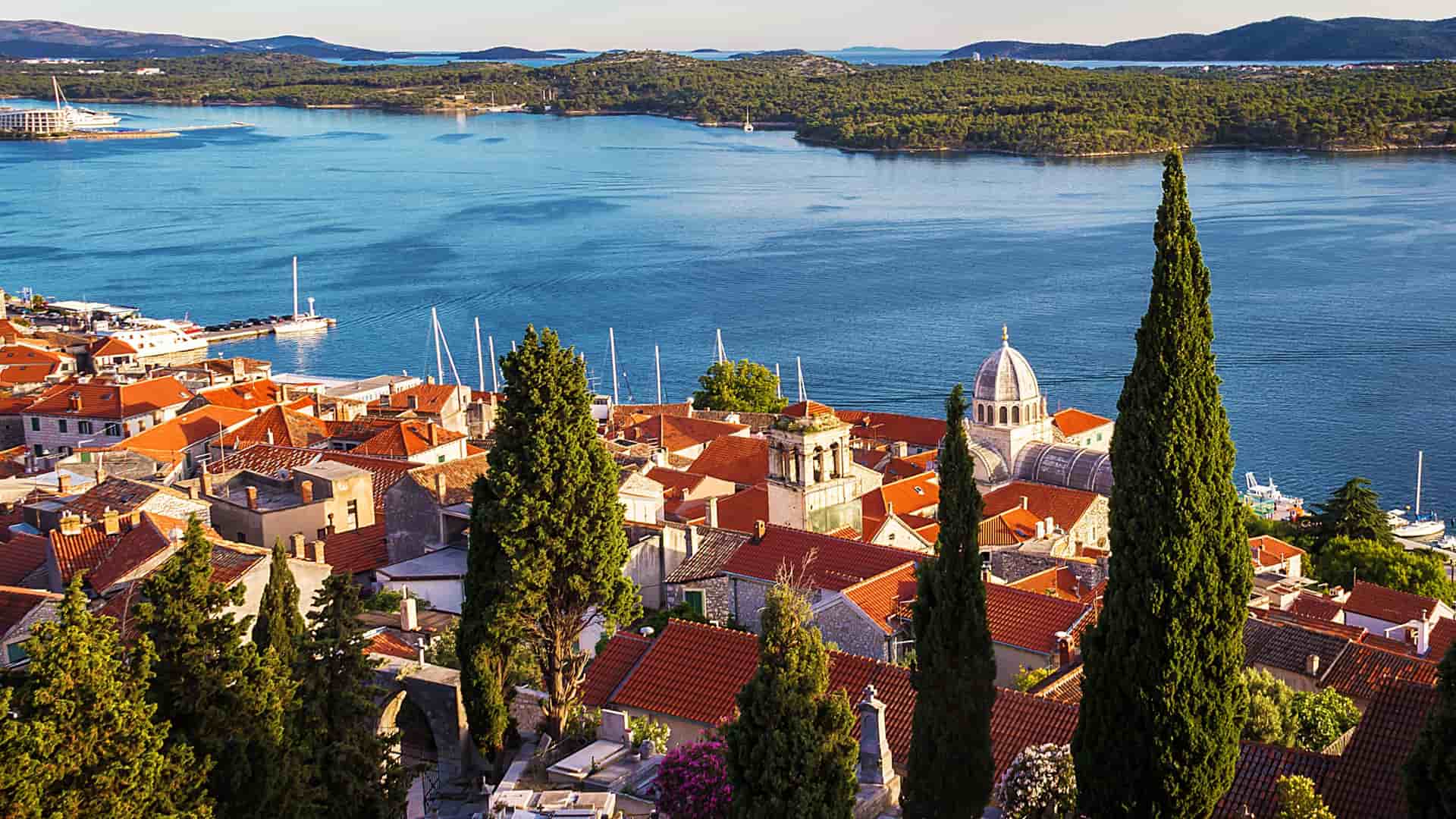 Buildings with terracotta roofs in front of the coastline in Sibenik, Croatia.