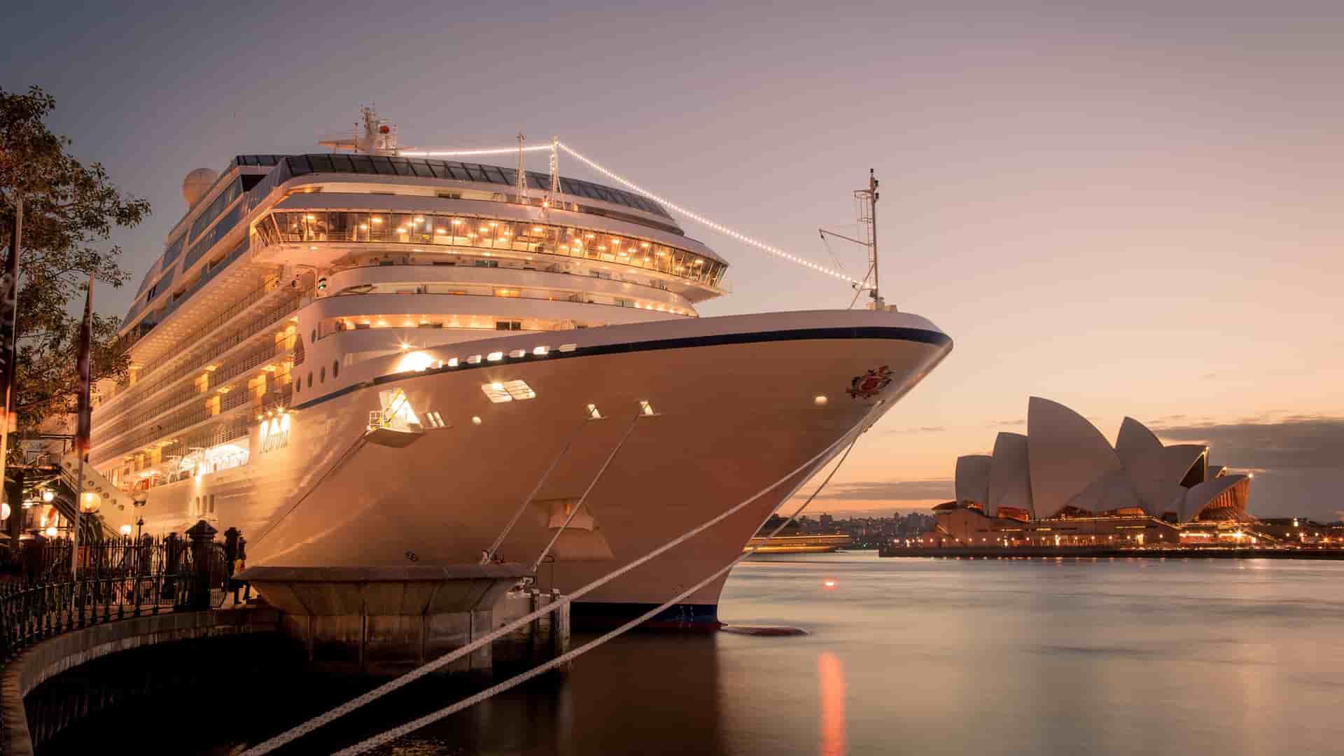Oceania cruise ship docked in Sydney Harbour at golden hour with the iconic Opera House in the background.