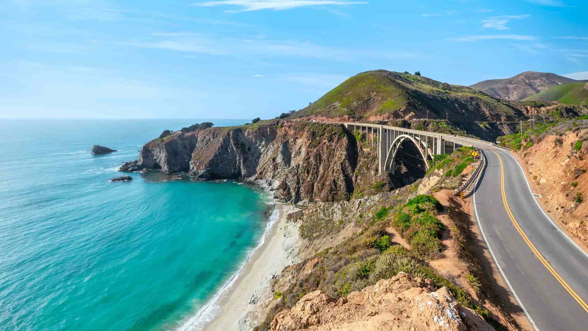 "A high-angle scenic view of the iconic Bixby Bridge in Monterey, California, spanning a coastal gorge along the beautiful Pacific Coast Highway.  "