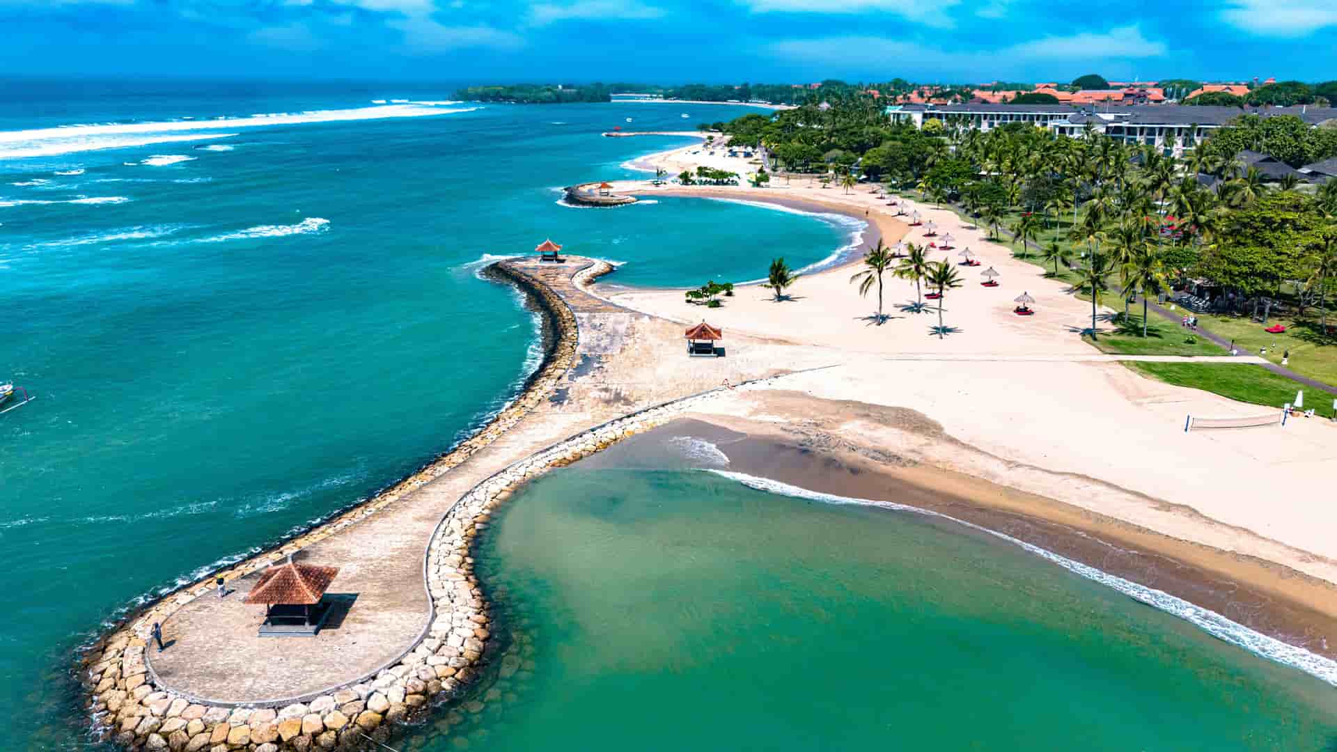 "An aerial view of the scenic coastline of Nusa Dua, Bali, Indonesia, with a serene lagoon and white sandy beach, a perfect tourist destination.  "
