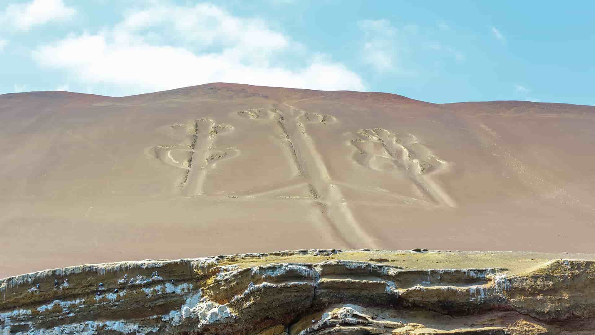 A clear view of the mysterious Candelabra of the Andes geoglyph, a pre-Inca etching carved into a sandy hillside, overlooking the Pacific Ocean near Pisco, Peru.