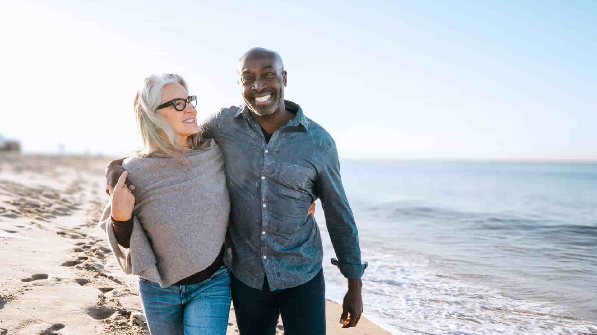 Smiling couple walking along the beach.