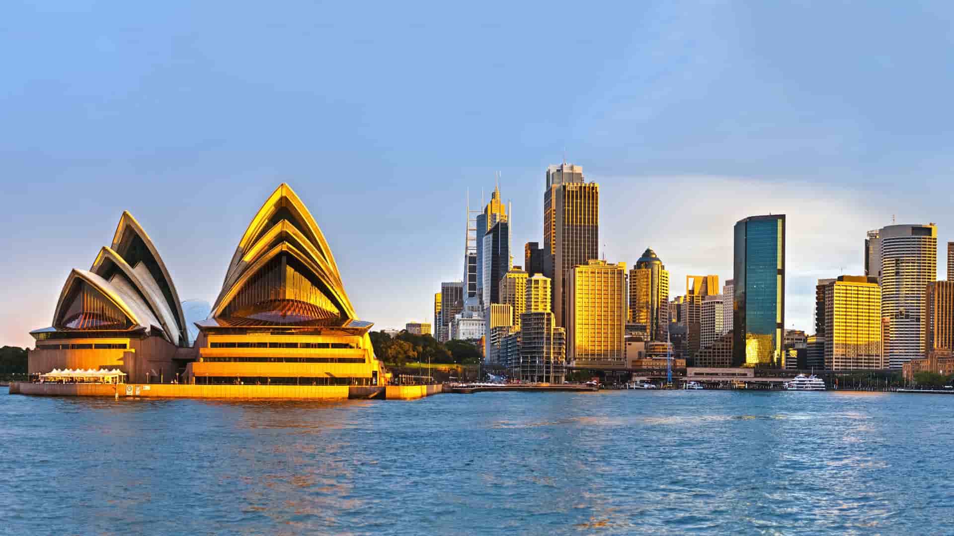 Sydney Opera House and city skyline at sunset.