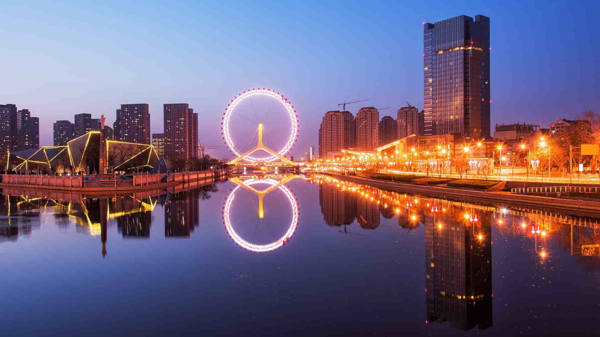 Tianjin Eye Ferris wheel reflecting in the Hai River at dusk.