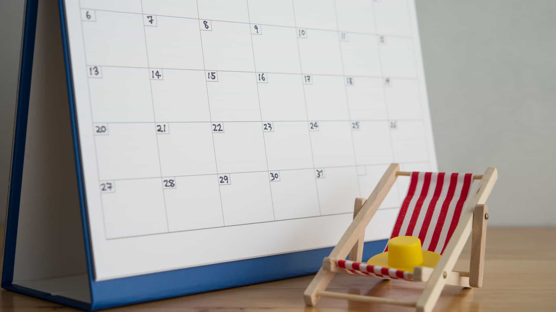 A miniature beach chair displayed next to a calendar on top of a table.
