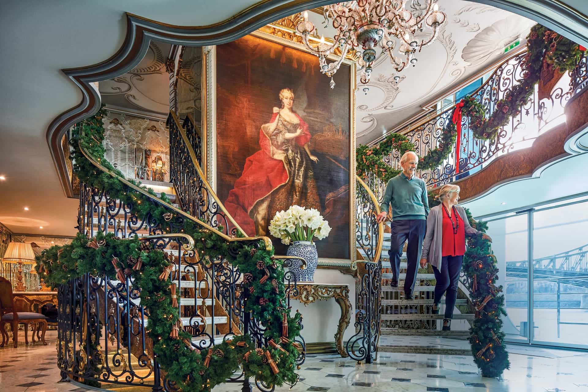 Older couple descending a split staircase on a Christmas themed cruise onboard Uniworld river ship, S.S. Maria Theresa.