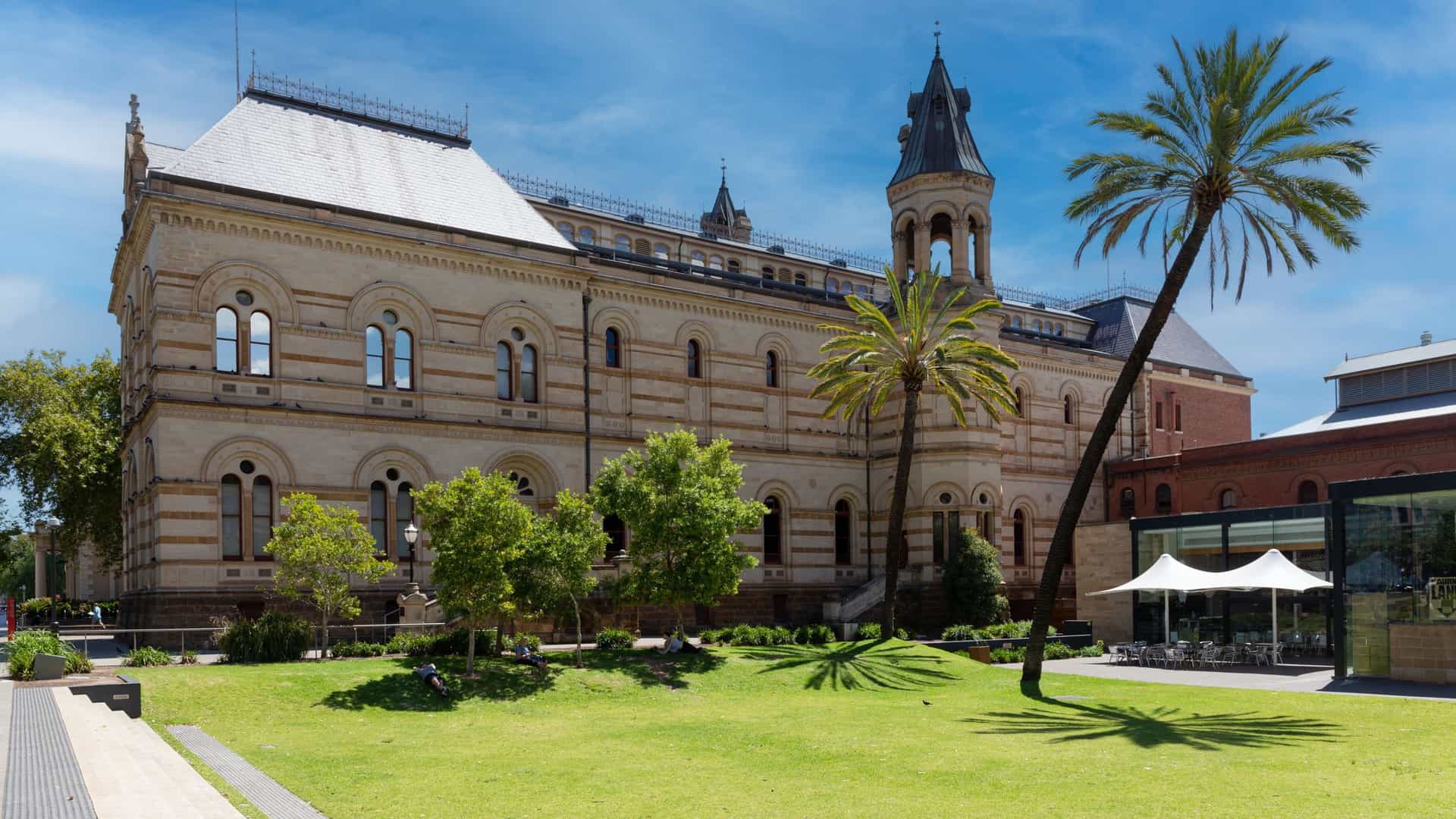 The grand, historic facade of the South Australian Museum in Adelaide, featuring Roman columns and classical architectural details. The building houses a major natural history collection in South Australia.
