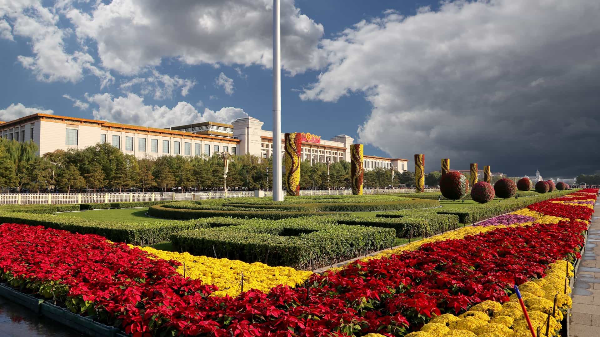  Tiananmen Square, a large city square in the center of Beijing, China. In the background is the Gate of Heavenly Peace (Tiananmen), an iconic red and yellow gate featuring a large portrait of Chairman Mao Zedong.
