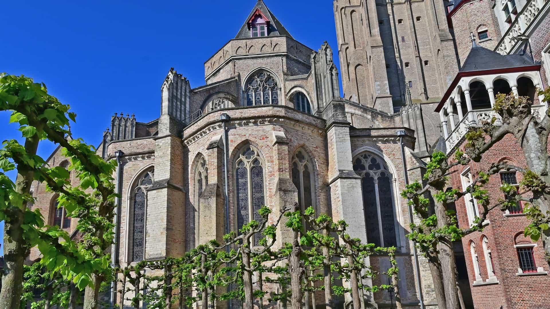 The Church of Our Lady (Onze-Lieve-Vrouwekerk) in Bruges, Belgium, featuring its towering brick spire—one of the tallest in the world—and the surrounding historic buildings.
