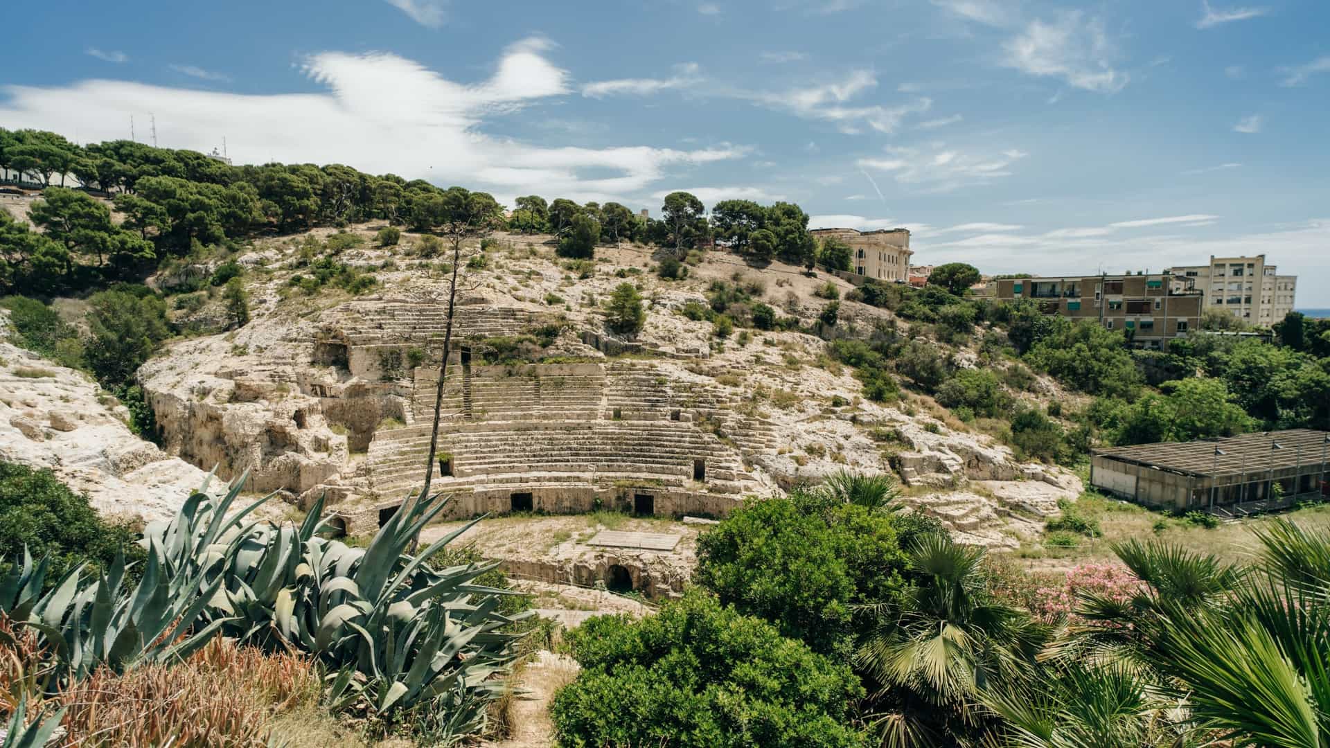 The remaining ruins of the Anfiteatro Romano di Cagliari (Roman Amphitheatre) in Cagliari, Sardinia, Italy, a large archaeological site carved into a hillside, once used for public spectacles.