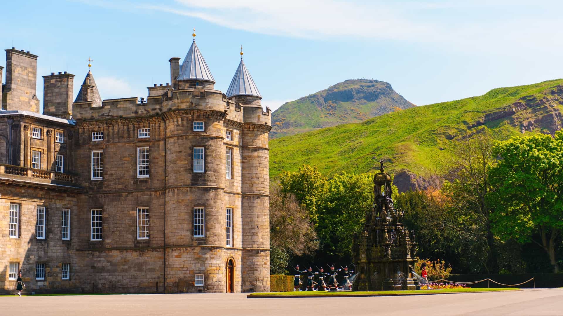  A view of the Palace of Holyroodhouse, the official residence of the British monarch in Scotland. The palace, with its historic architecture, is shown in a formal setting, with a paved courtyard and a manicured lawn in the foreground.