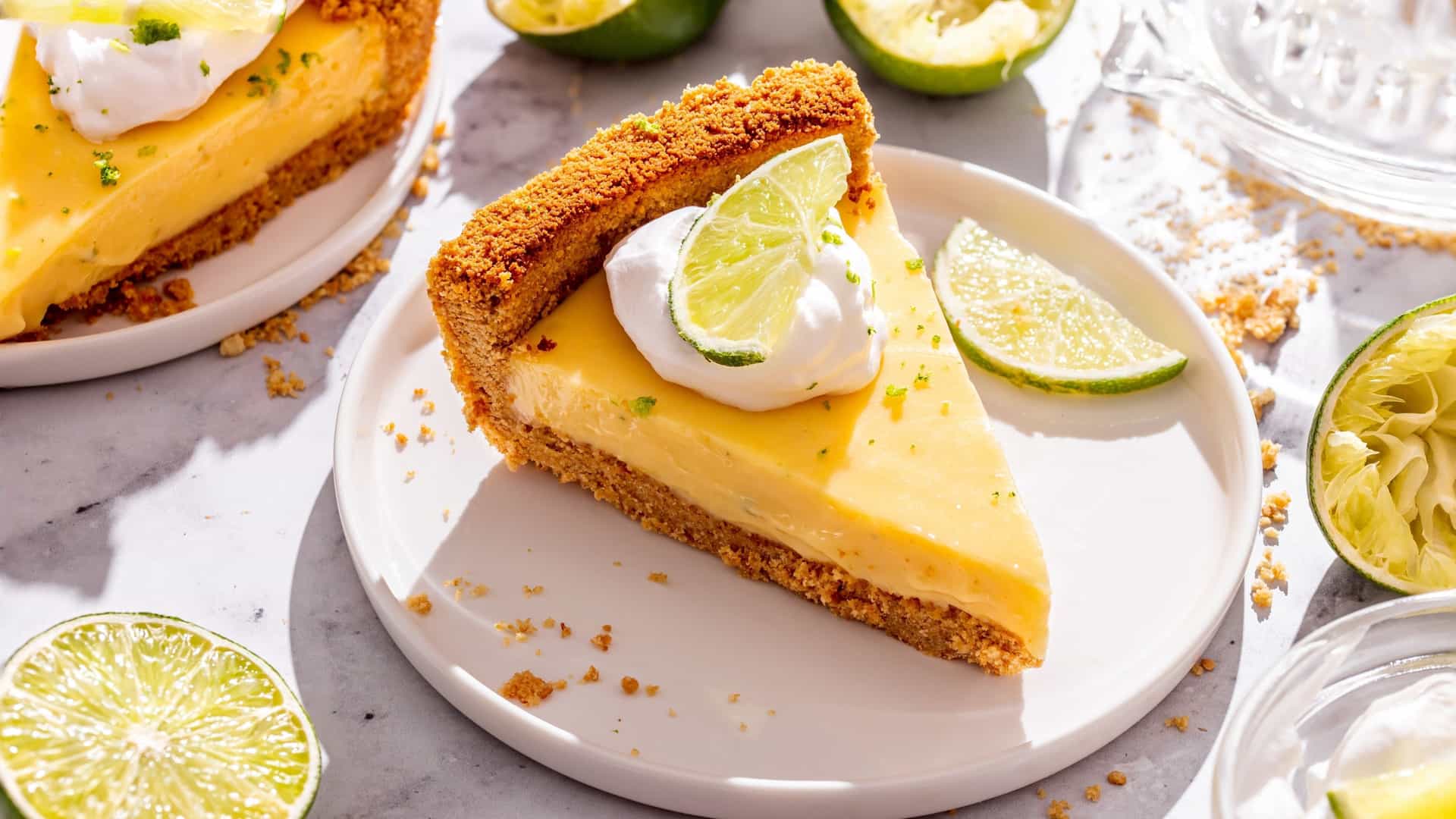 A slice of key lime pie with a bright green custard filling, a graham cracker crust, and a generous dollop of white whipped cream on top, garnished with a spiral of green lime zest.