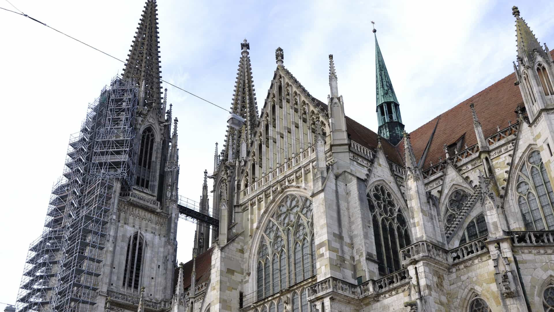  The impressive Gothic architecture of Saint Peter Cathedral in Regensburg, Germany, showcasing its towering twin spires and ornate, detailed facade against a clear sky.