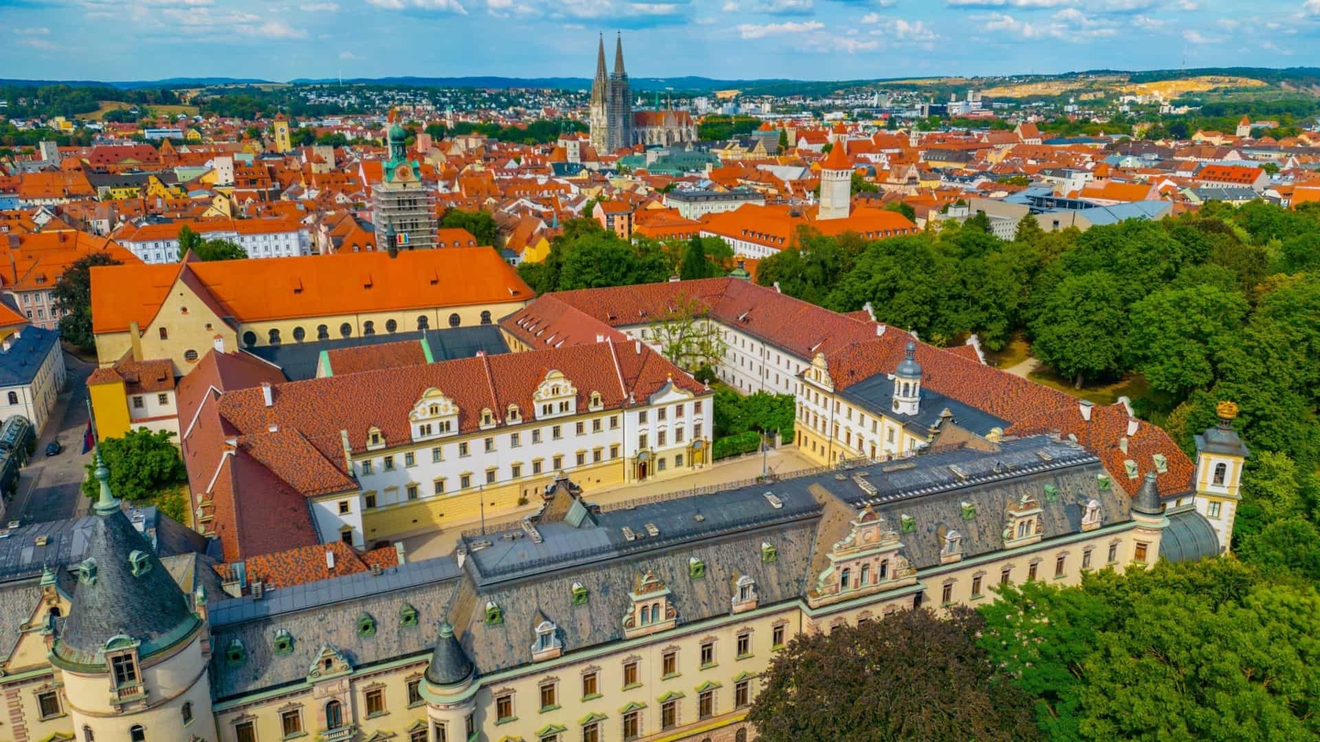 A panorama view of the St. Emmeram Palace (also known as the Thurn und Taxis Palace) in Regensburg, Germany. The expansive building complex, which was converted from the former Imperial Abbey of St. Emmeram, is a prominent example of German aristocratic architecture. The palace, featuring various architectural styles, including the neo-Gothic south wing, is set against the backdrop of the city and serves as the largest privately inhabited palace in Germany.