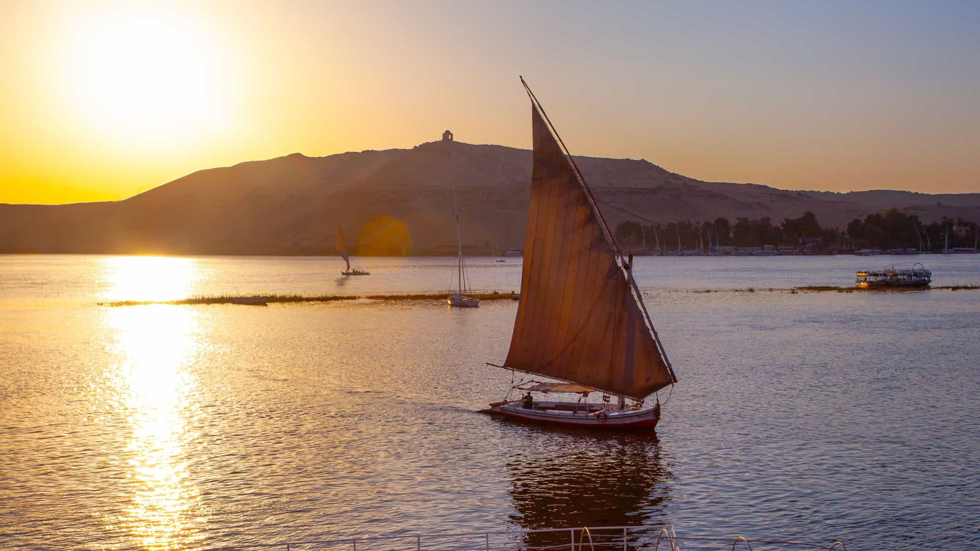 Explora Journeys view of a traditional sailing felucca on the Nile River at sunset in Egypt.