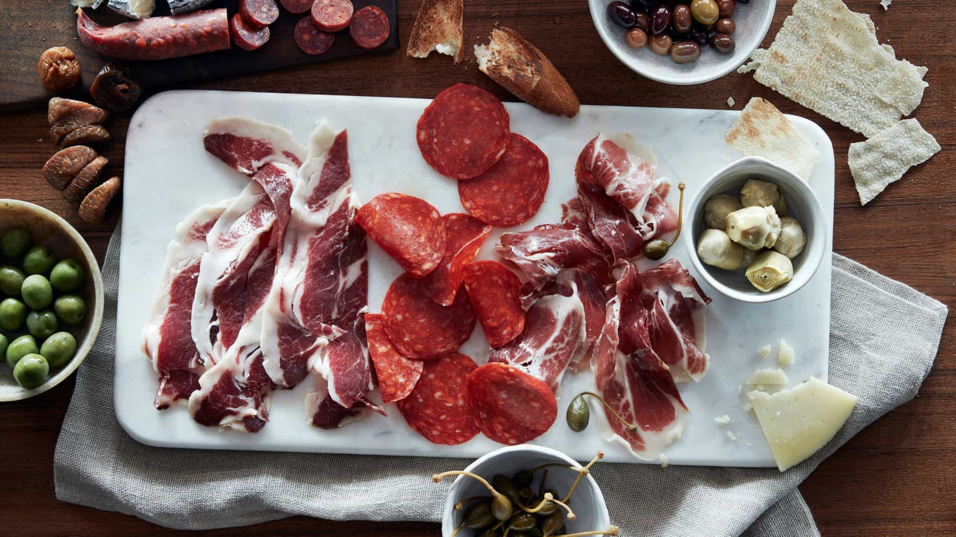 A cutting board of artisan meats and ingredients at Pincho Tapas Bar on Norwegian Escape.