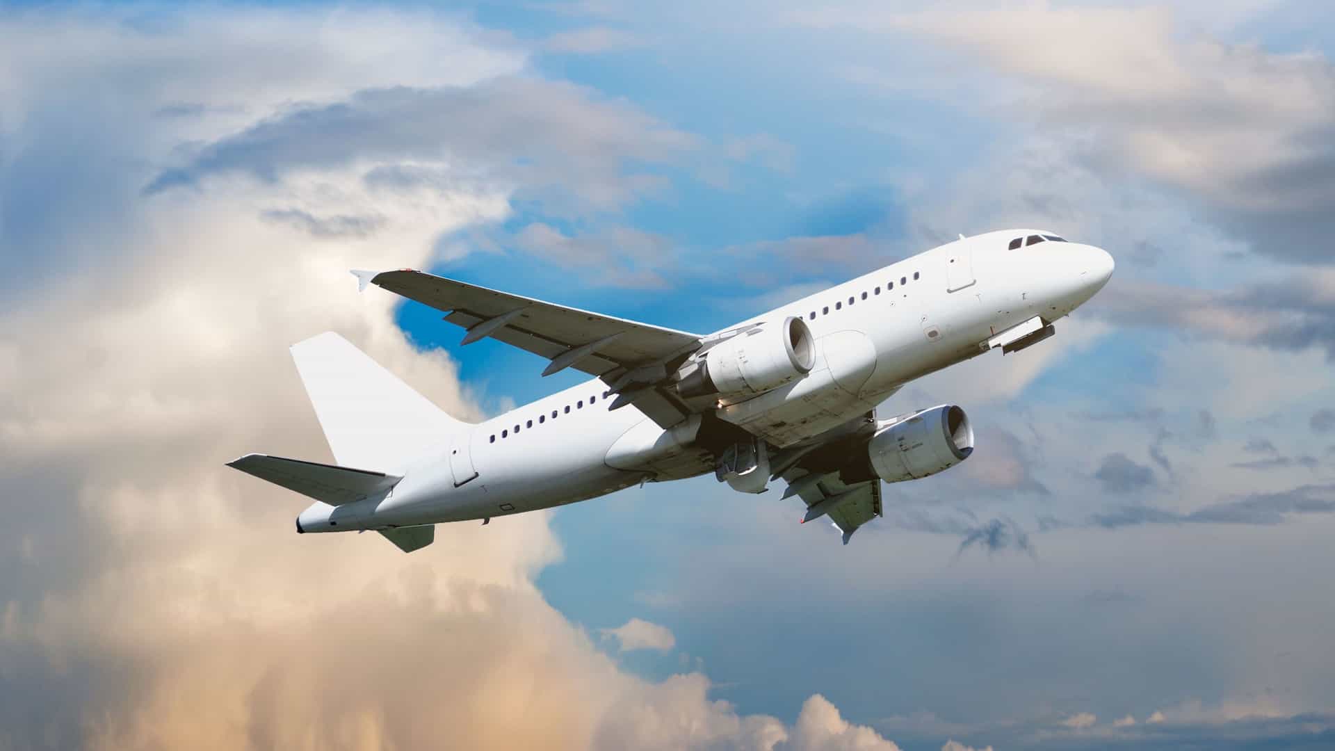 A generic white passenger airplane ascends into a vibrant, cloudy sky, with its engines visible and landing gear retracting.