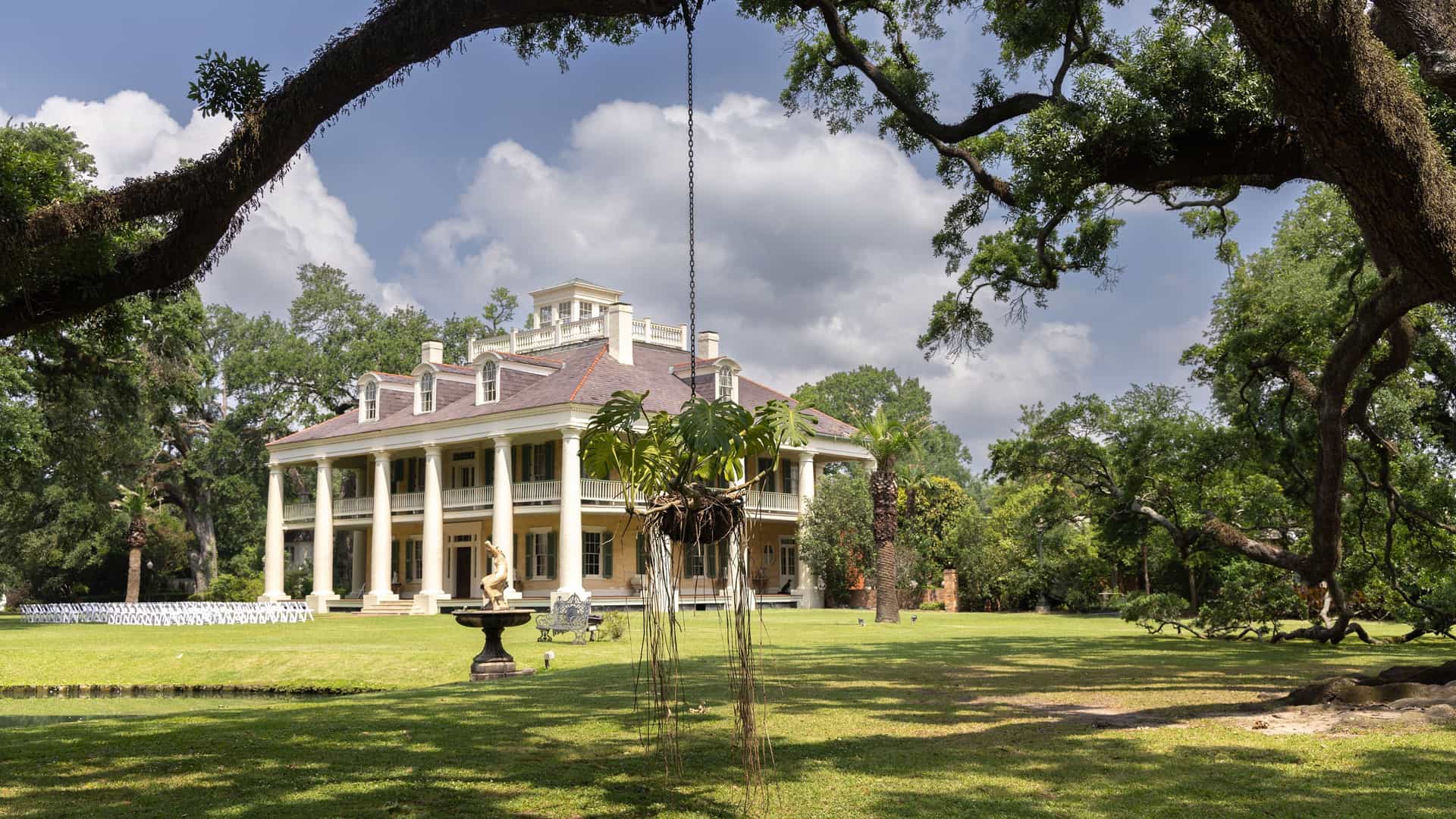 The majestic Houmas House Plantation, a historic Antebellum mansion in Darrow, Louisiana, is beautifully framed by a large live oak tree.