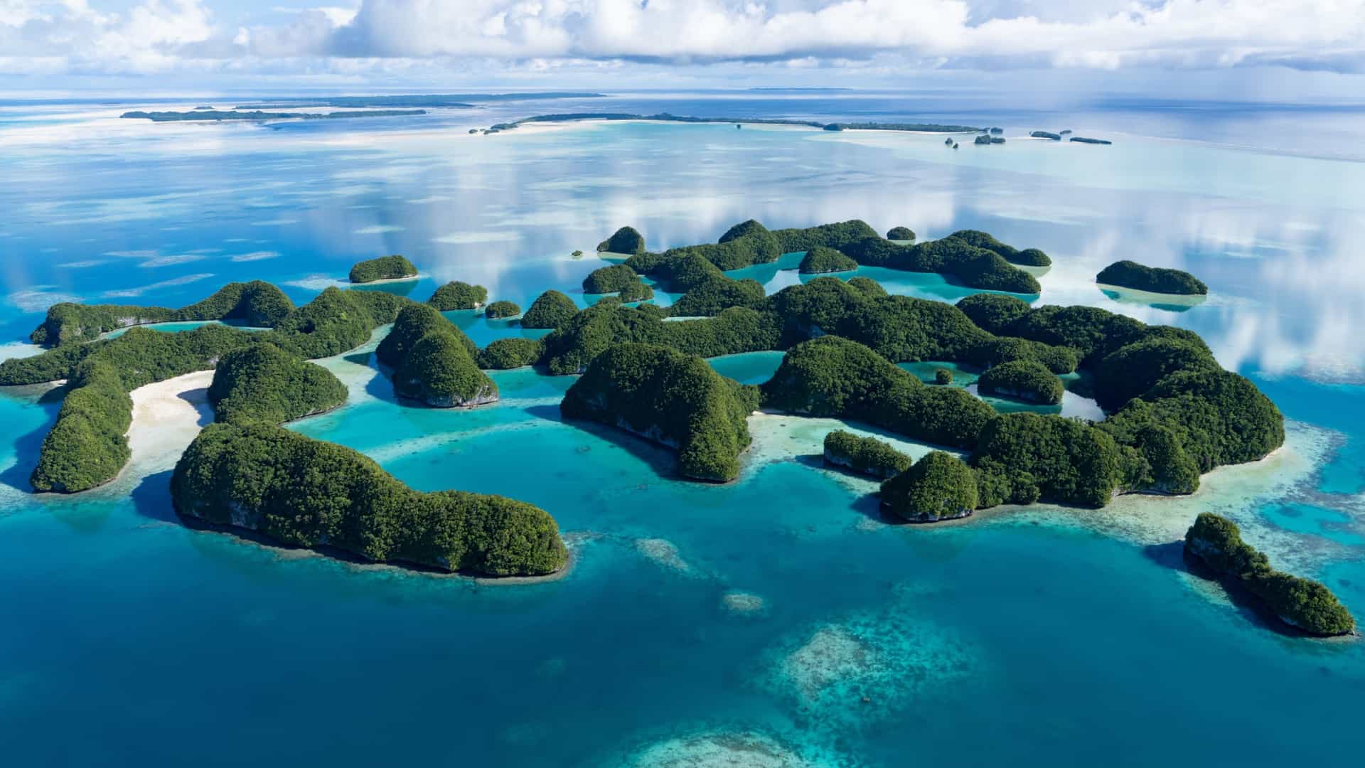 An aerial view of the small, lush green islets of Kapingamarangi Atoll, Micronesia, surrounded by clear turquoise water.