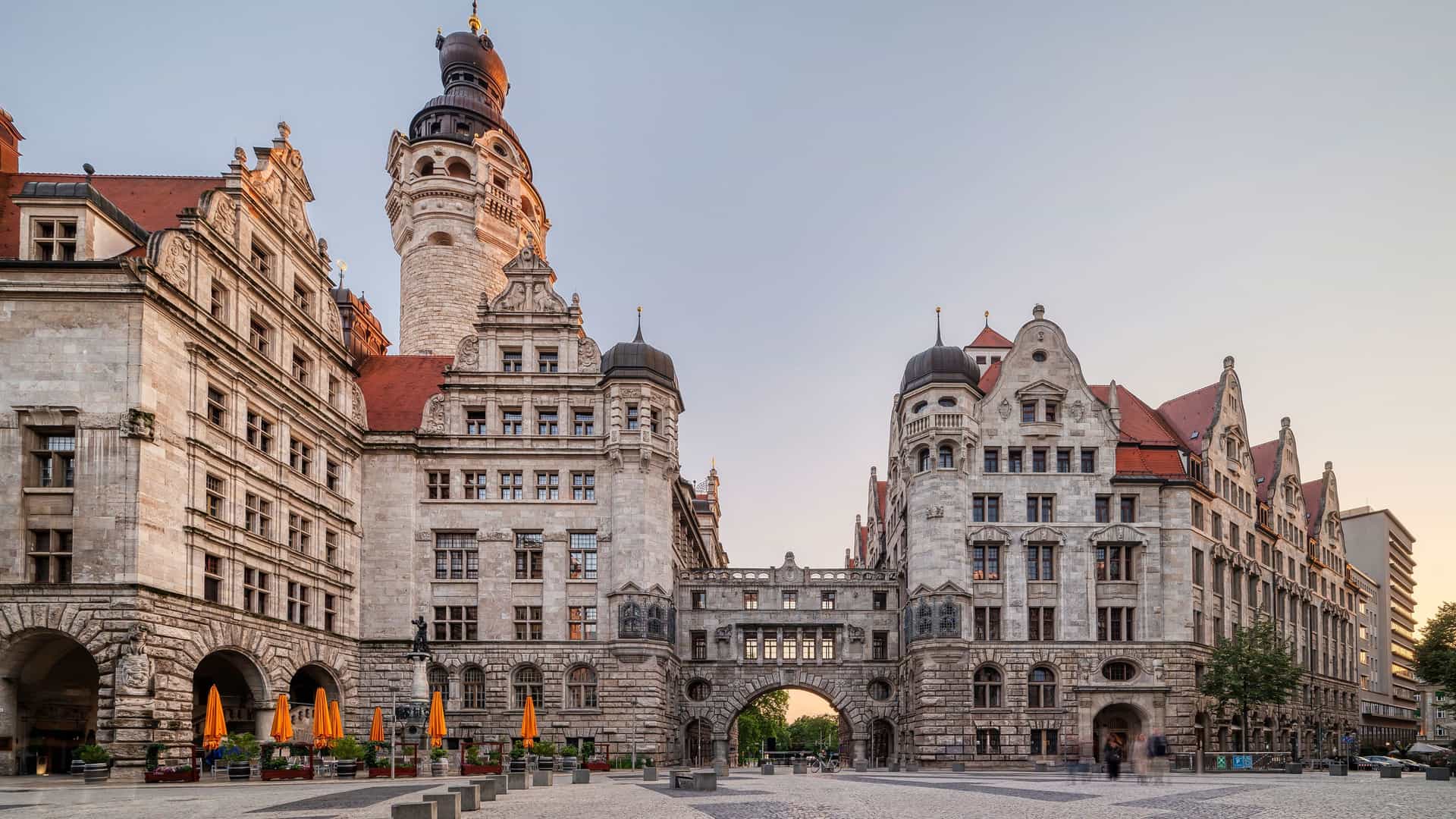 "A scenic street-level view of the historic Leipzig New Town Hall (Neues Rathaus) and the city square, showcasing its stunning Renaissance architecture and prominent clock tower. "