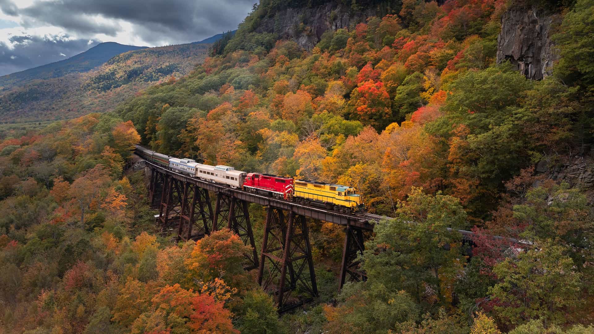 A train crossing the Frankenstein Trestle, a historic railway bridge, in the scenic White Mountains of North Conway, New Hampshire, during the autumn season.