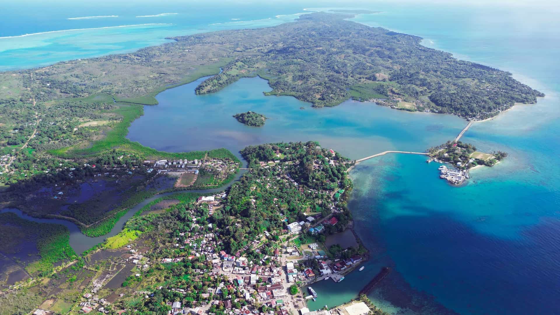 An aerial view of Sainte-Marie Island, or Nosy Boraha, showing a lush green landscape, a calm turquoise lagoon, and the village of Ambodifotatra along the coast.