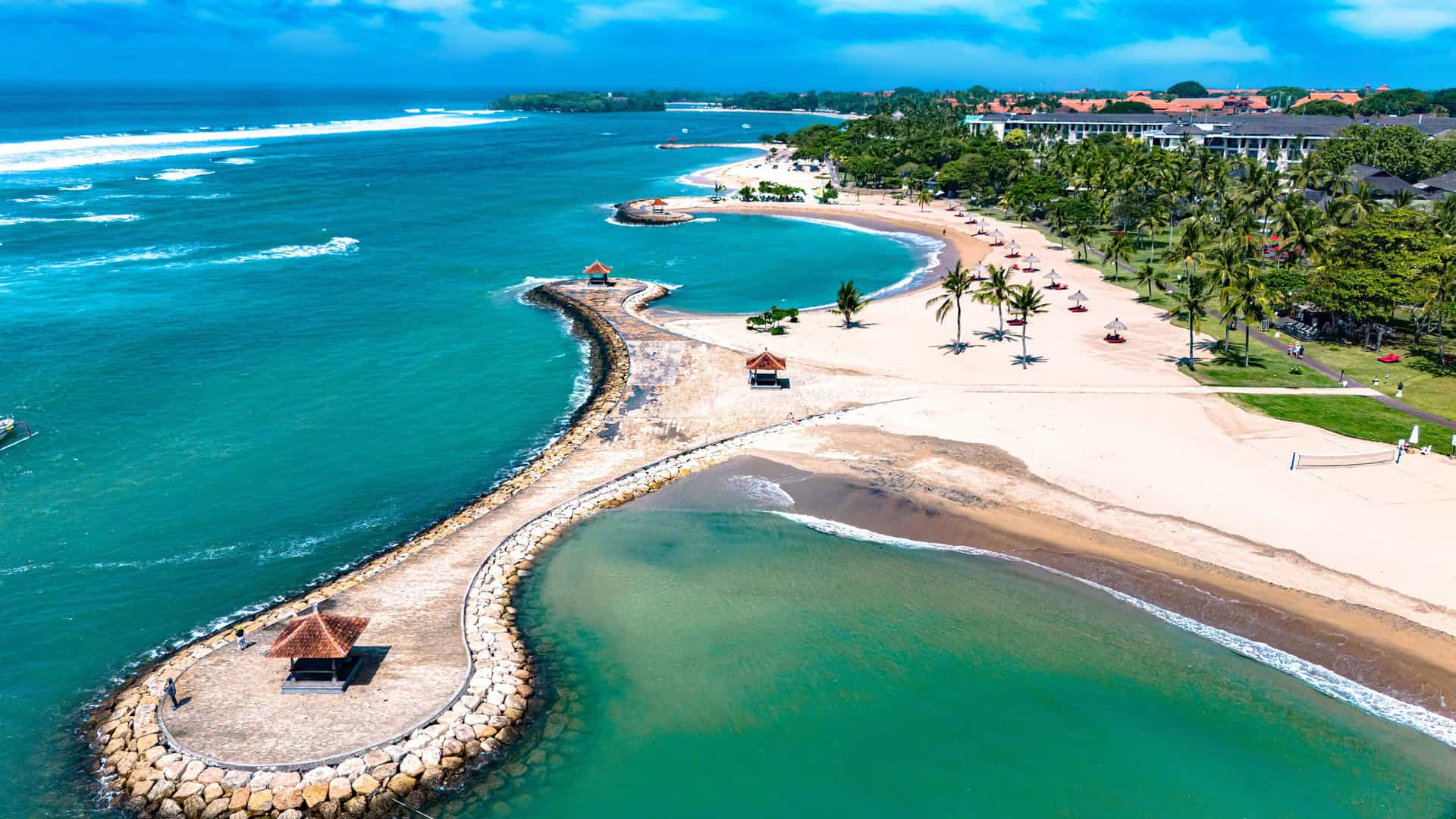 "An aerial view of the scenic coastline of Nusa Dua, Bali, Indonesia, with a serene lagoon and white sandy beach, a perfect tourist destination.  "