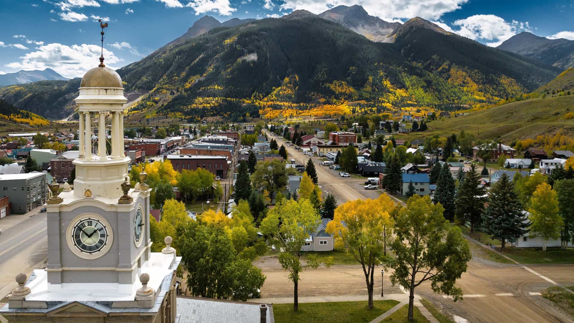 The clock tower of Silverton, Colorado, overlooks the historic mining town and mountains displaying vibrant autumn foliage.