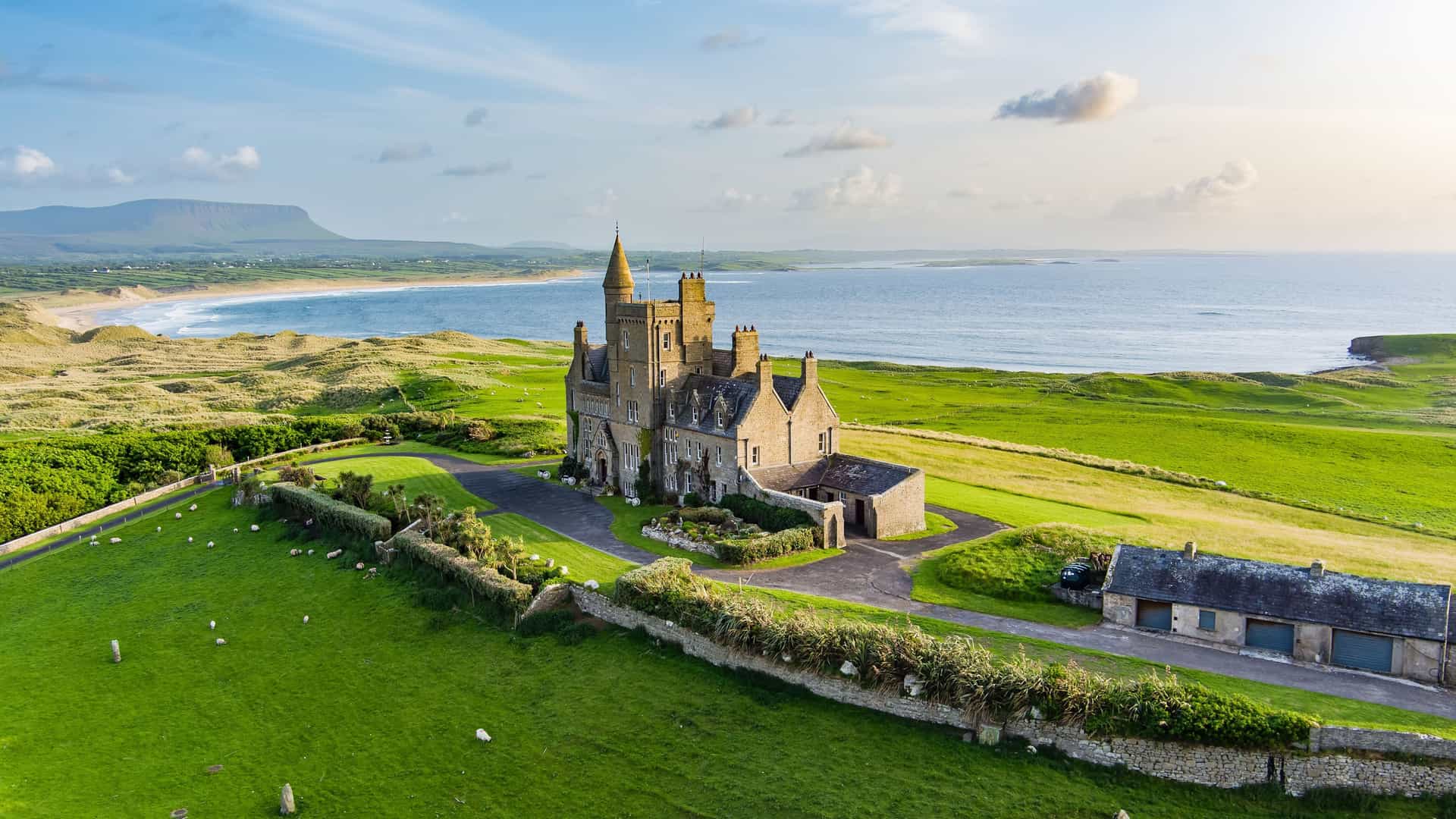 "An aerial view of the iconic Mullaghmore Castle in Sligo, Ireland, a historic castle on a lush green hilltop overlooking the Atlantic Ocean.  "