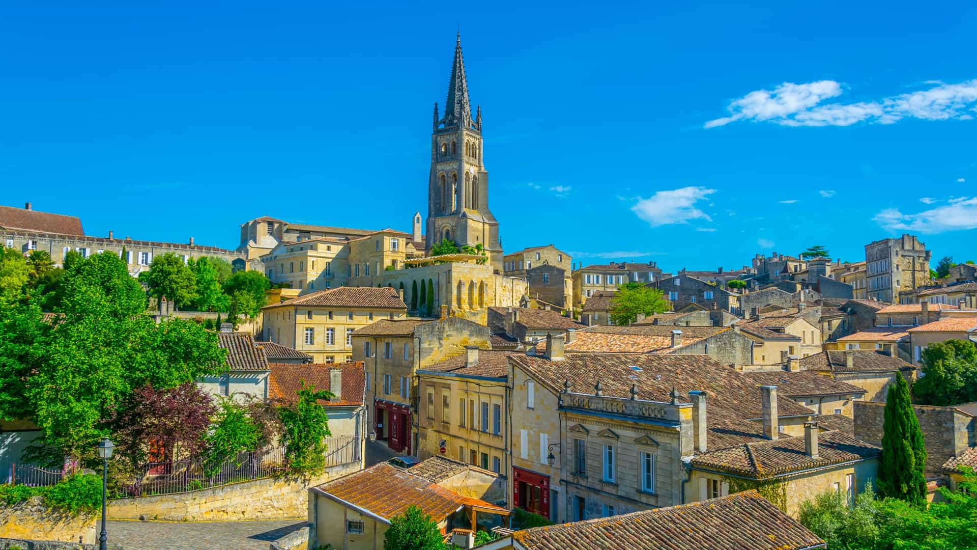 A stunning view of the historic town of St. Emilion, France, with its medieval buildings and the iconic bell tower of the Monolithic Church rising above the rooftops.