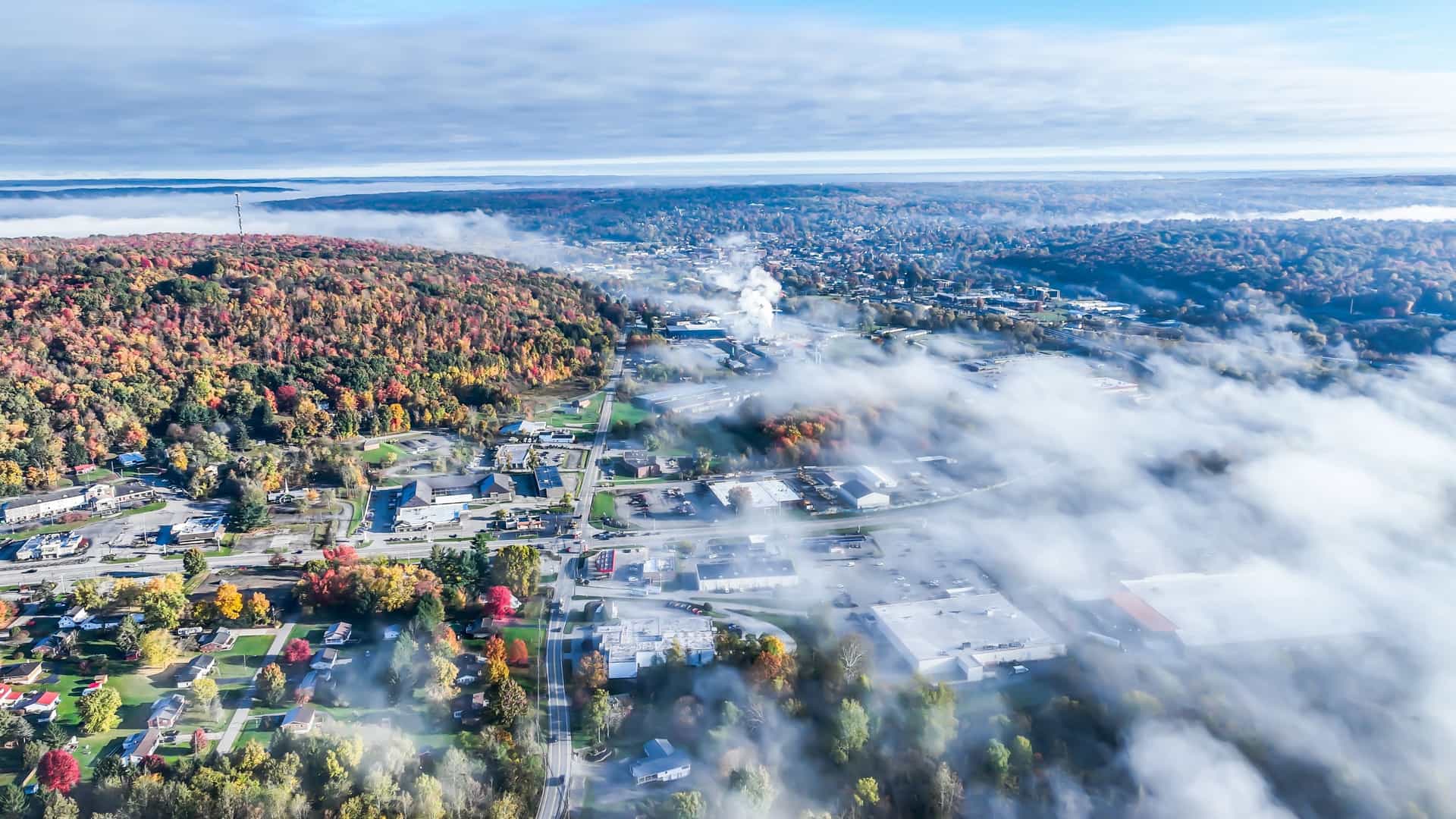 An aerial view of Stratton, Vermont, on a misty autumn day, with colorful fall foliage surrounding the town buildings.