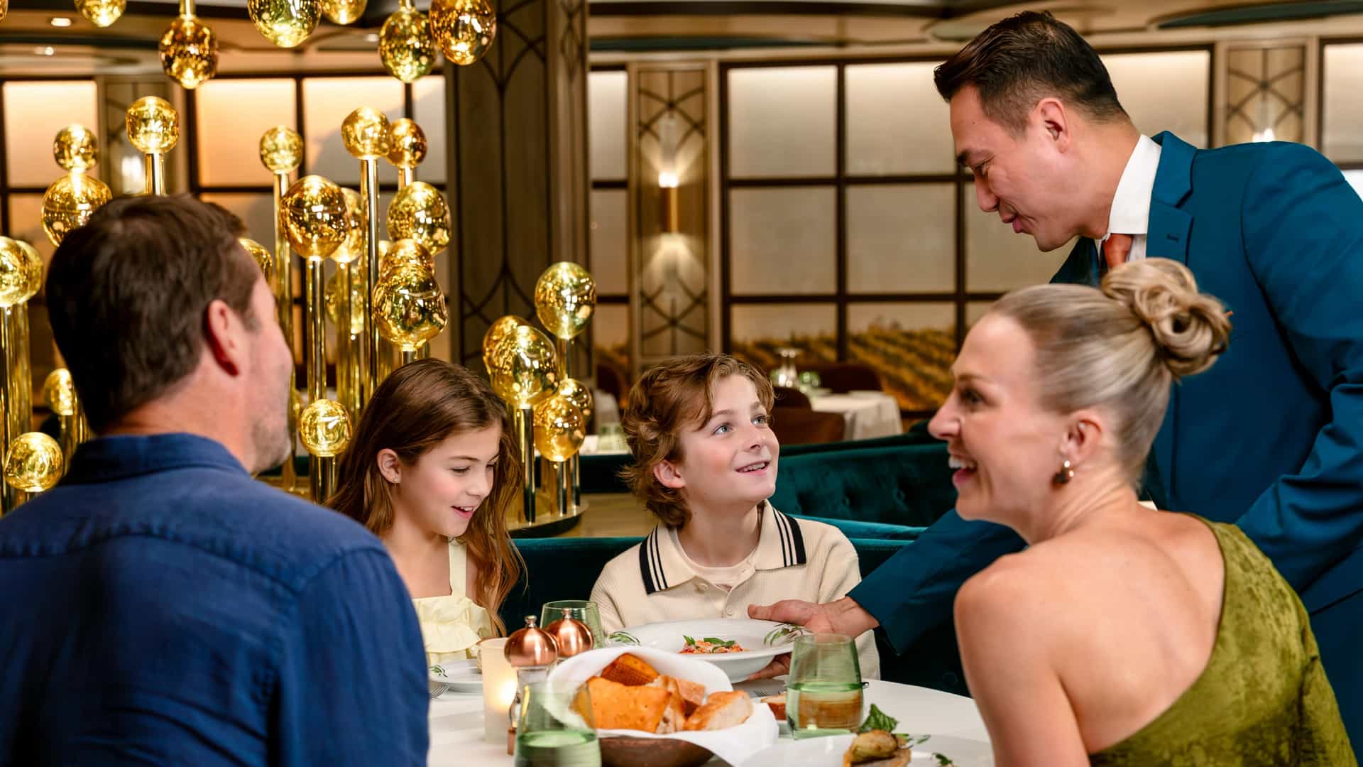 A waiter serving a family of four at a dinner table in Sabatini's Italian restaurant onboard a Princess Cruises ship.