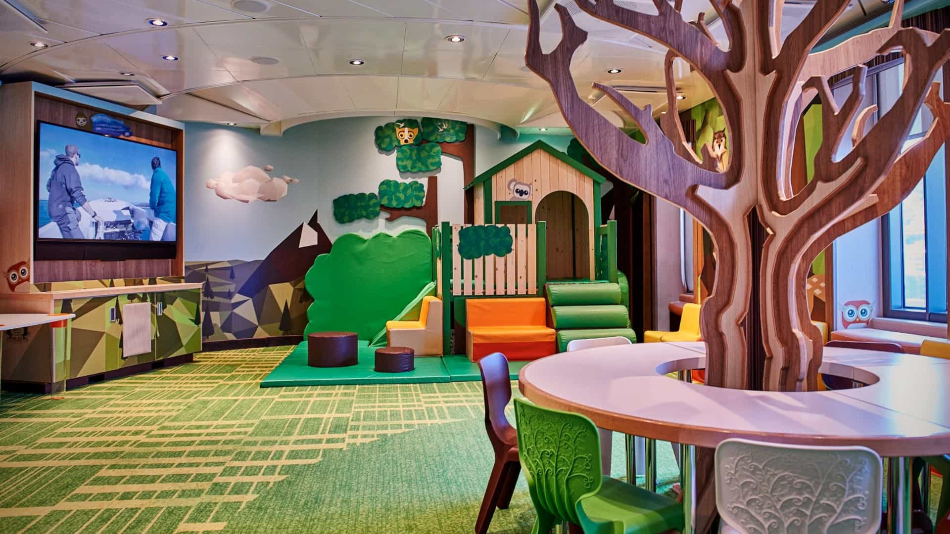 The Treehouse youth center on a Princess Cruises ship, featuring a forest-themed indoor play area with a wooden tree structure, small slide, and activity tables for kids.