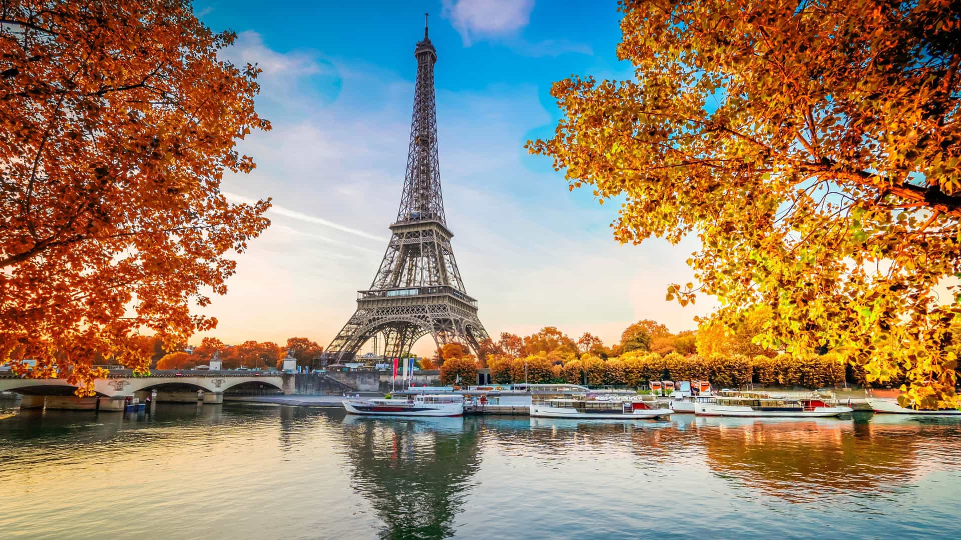 The iconic Eiffel Tower standing over the Seine River in Paris, France, with boats in the foreground, a breathtaking highlight of a Viking River cruise.