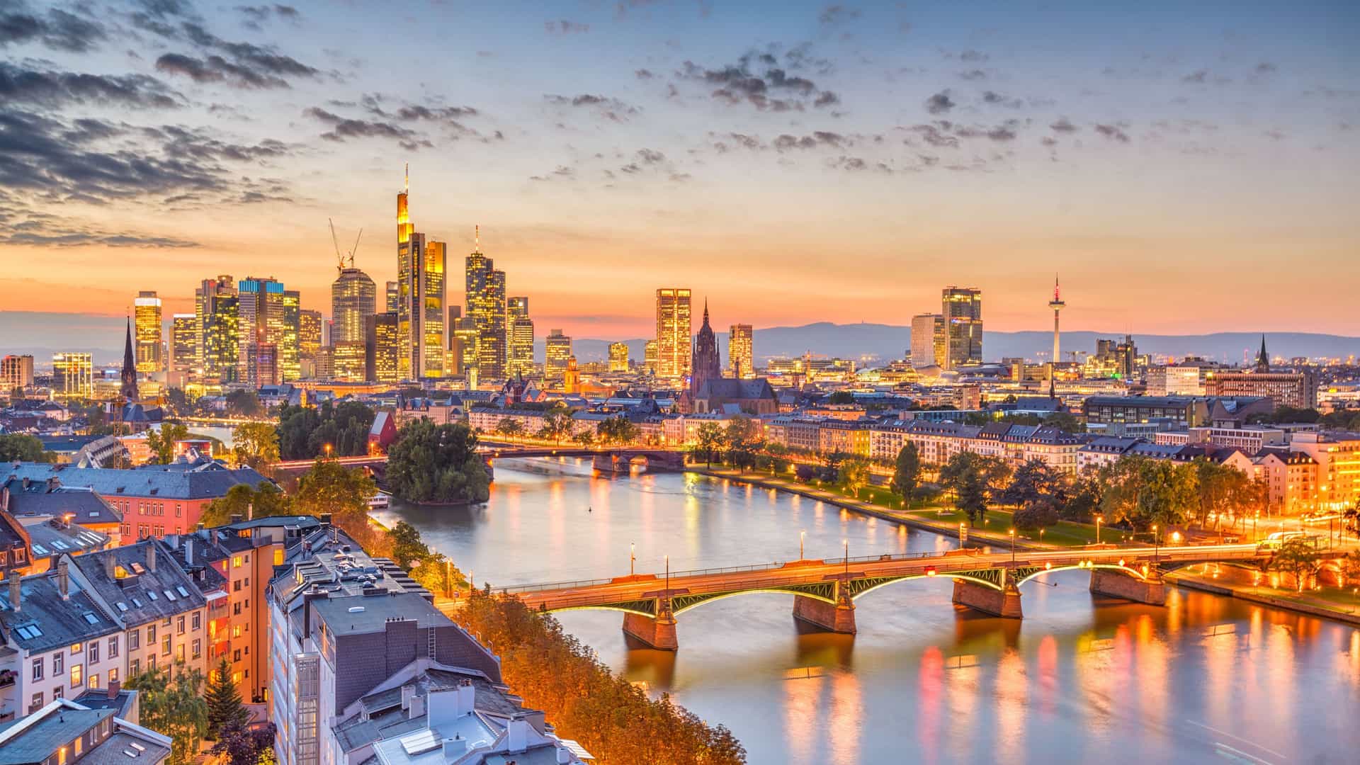 The illuminated skyline of Frankfurt, Germany, reflecting on the Main River at dusk, a vibrant city to explore on a Viking River cruise.