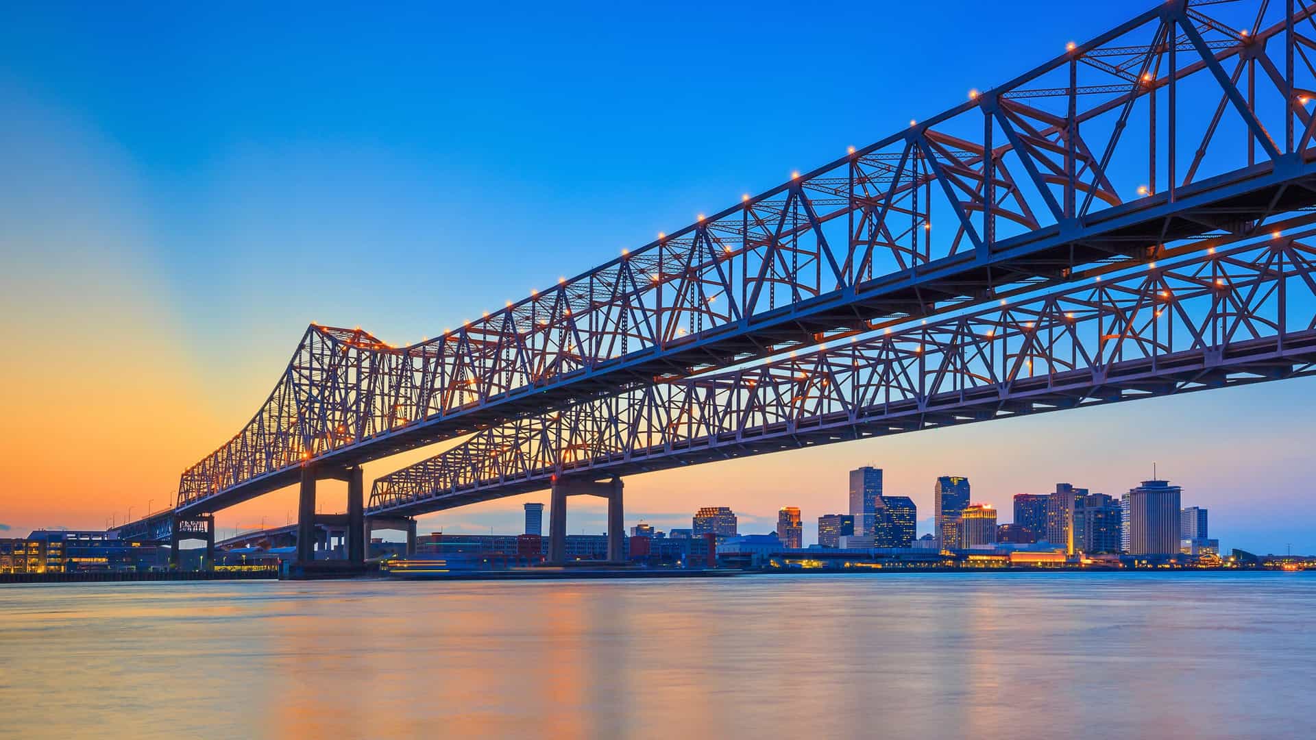 The illuminated skyline of New Orleans, Louisiana, and the Crescent City Connection bridge over the Mississippi River at sunset, a popular port of call on a Viking River cruise.
