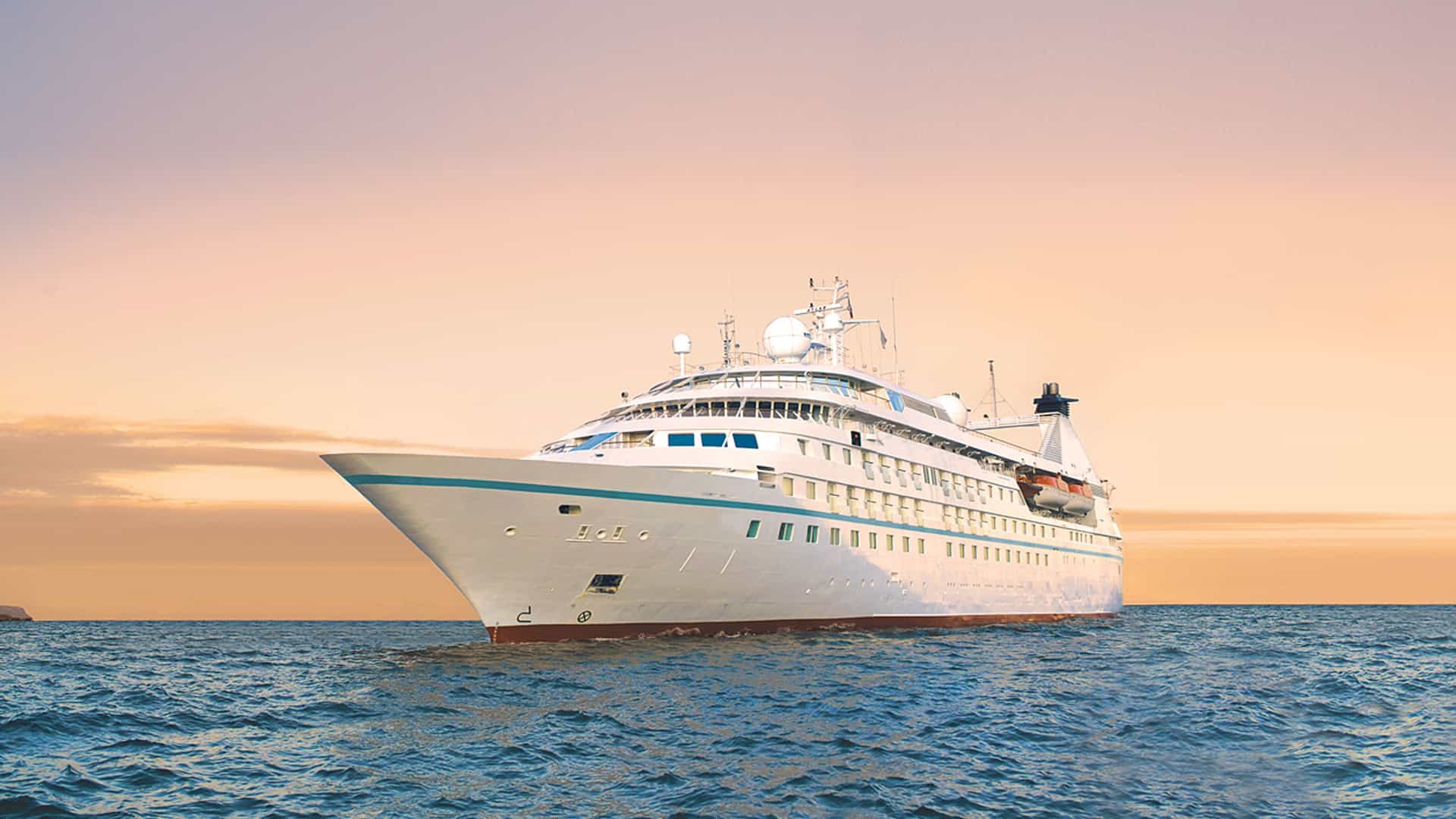 Windstar's Star Breeze cruise ship sailing at sunset.
