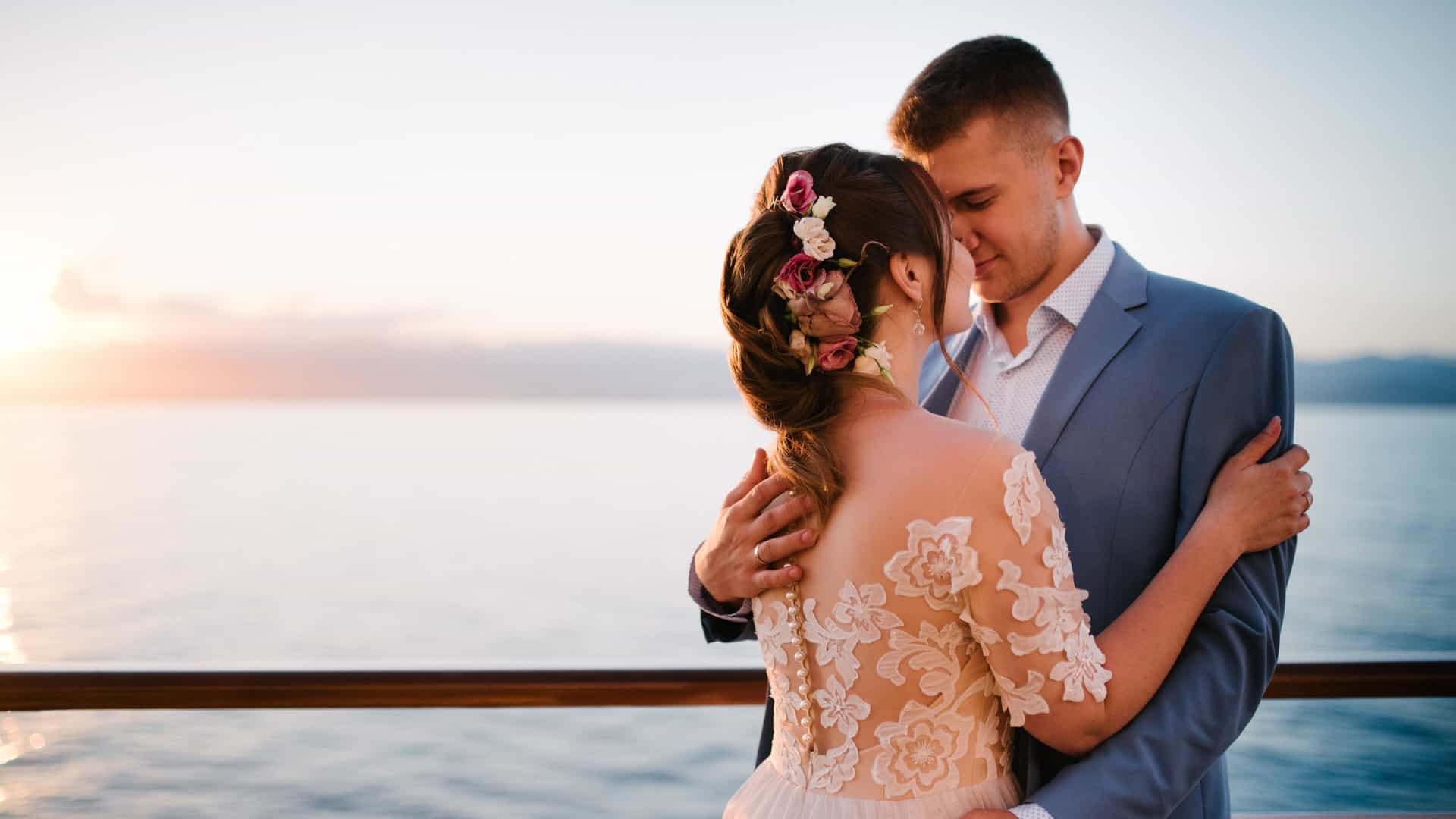 Young newly weds watching the sun set together on a cruise.