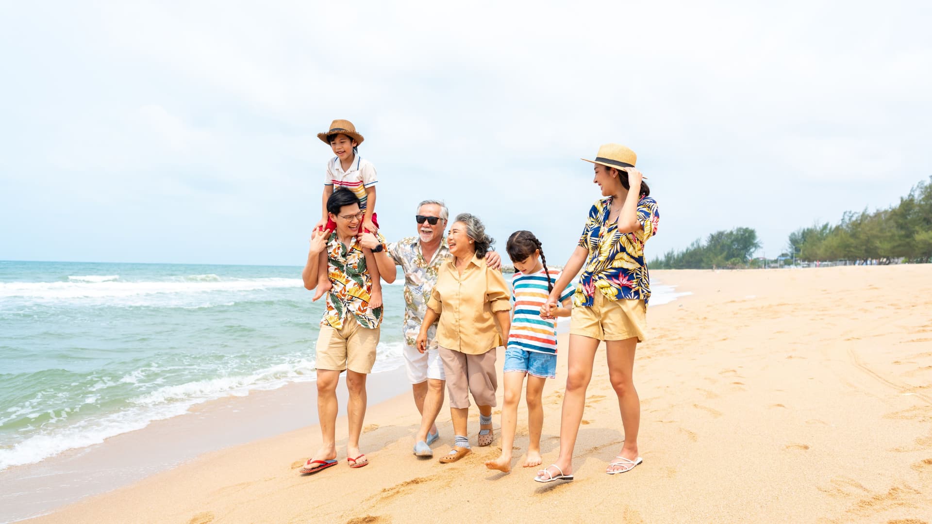 Multi-generational family walking together along the beach.
