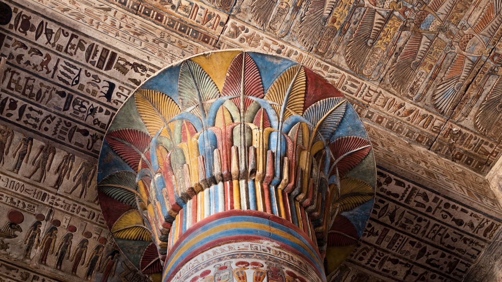 A vibrant, detailed close-up shot of a massive, painted column capital inside the ancient Temple of Esna, showcasing well-preserved Egyptian hieroglyphs and colorful decorations.