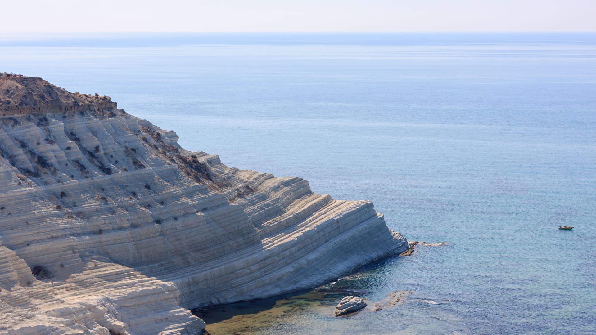A stunning close-up of the Scala dei Turchi white marl cliff near Porto Empedocle, Sicily, jutting out into the crystal-clear turquoise Mediterranean Sea.