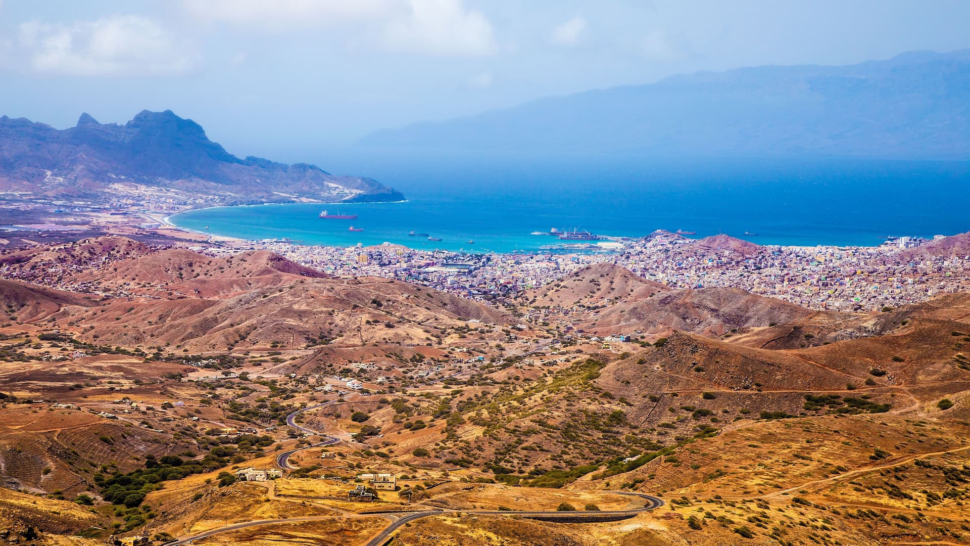 A breathtaking high-angle view of the large harbor and city of Porto Grande, São Vicente, Cape Verde, nestled between arid mountains and the serene Atlantic Ocean.