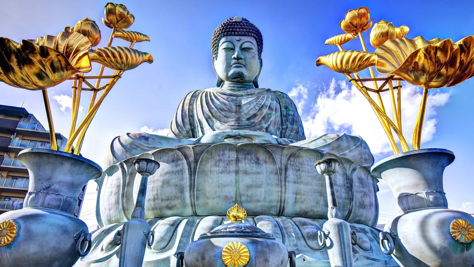 A large golden Buddha statue surrounded by vibrant gold flowers.