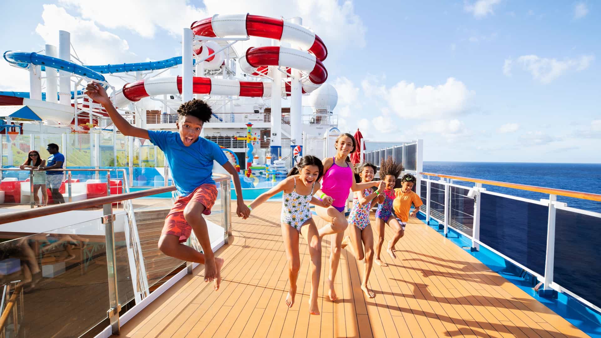 A group of children happily leaping on a Carnival cruise ship deck.