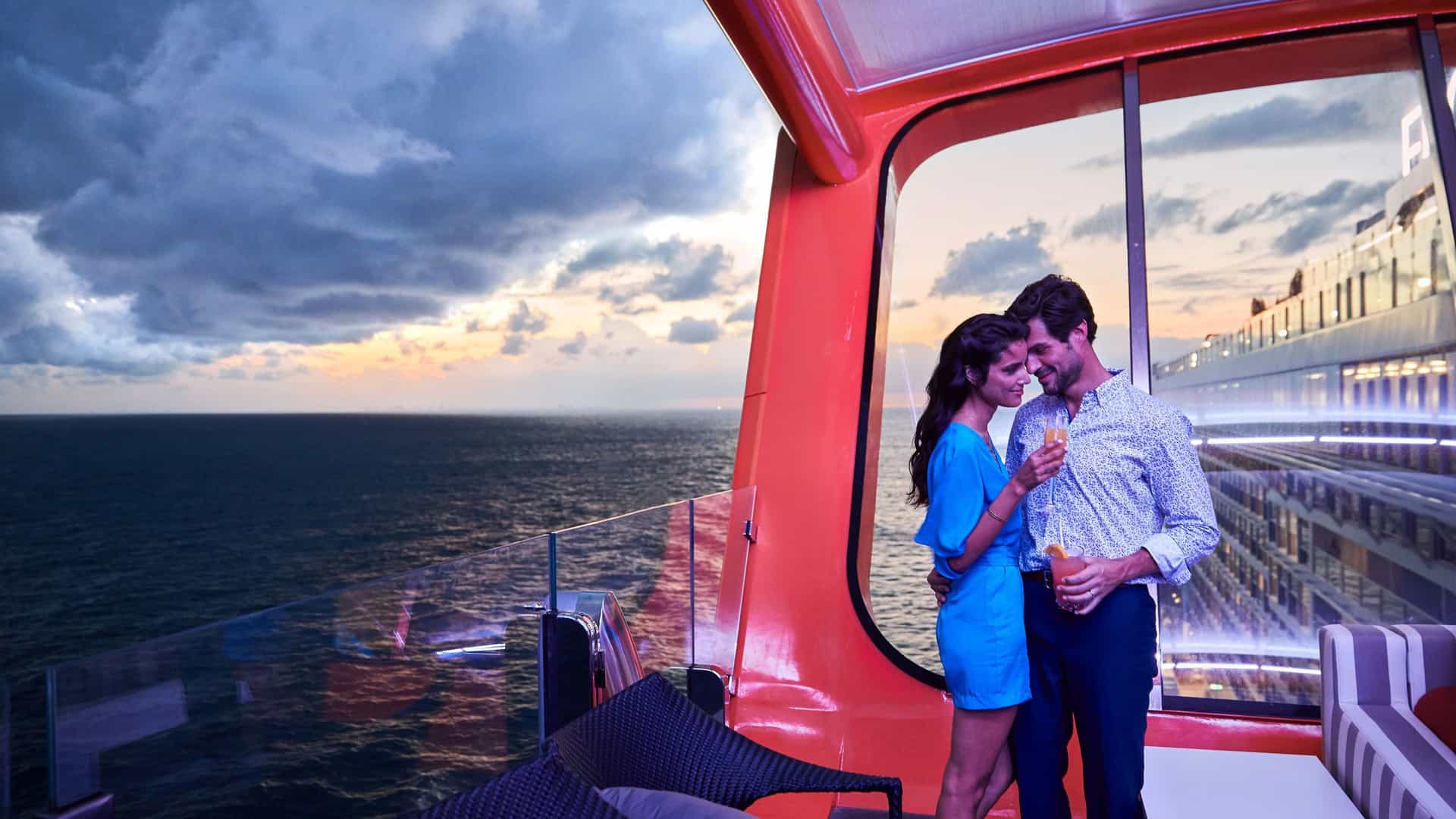 A couple kissing on a Celebrity Cruises Magic Carpet with the sea stretching out behind them.