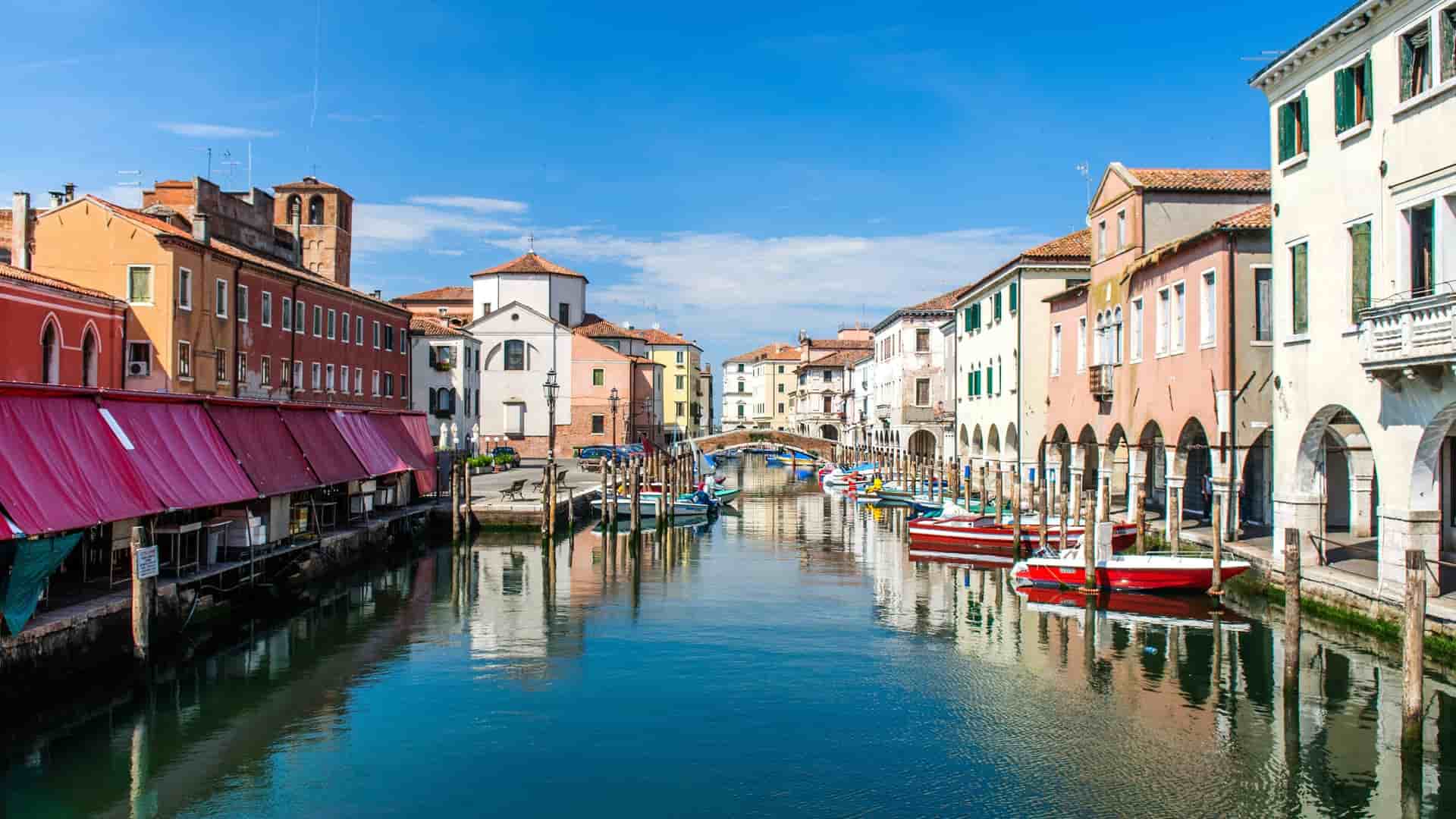 Colorful buildings and boats along a canal in Chioggia, Italy.