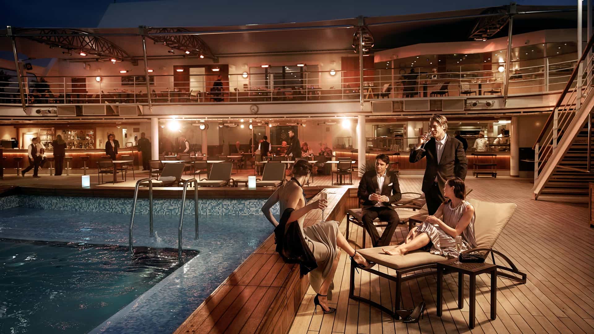 Couples enjoying cocktails by the pool at night on a Silversea cruise.