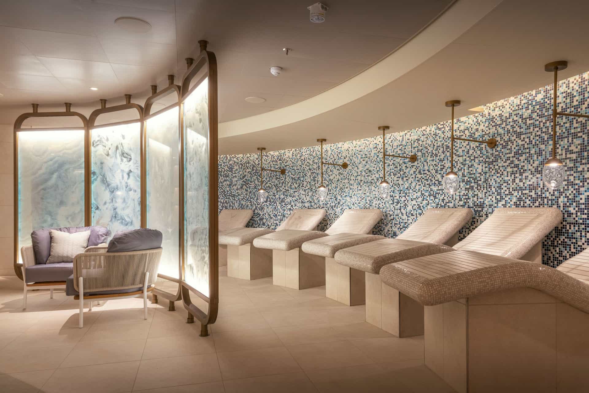 Modern relaxation room in the Mareel Spa featuring curved tiled heated loungers, soft mood lighting, and decorative privacy screens.
