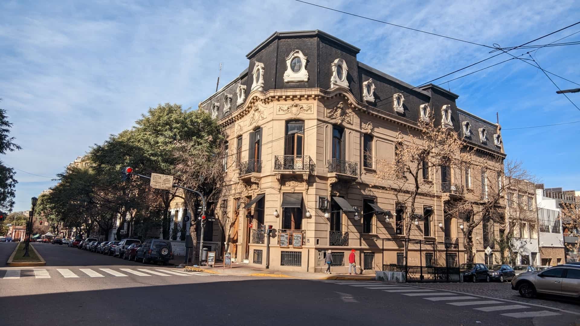 A classic view of a street in San Telmo, the oldest neighborhood in the Autonomous City of Buenos Aires (CABA), Argentina. The image features historic, colonial style architecture with colorful facades, traditional iron balconies, and charming details. The street has a vintage, bohemian atmosphere, characteristic of this area known for its tango, antique shops, and cobblestone streets.